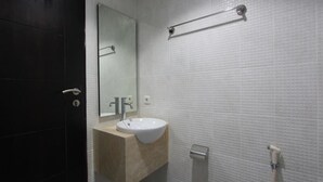 Een badkamer met een witte wastafel, een spiegel en een handdoekhouder.