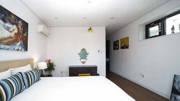 A bedroom with a bed, a dresser, a mirror, and a painting on the wall.
