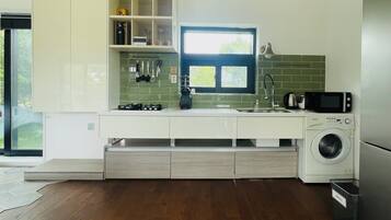 A modern kitchen with a built-in washing machine, a window with a view, and a countertop with various appliances.