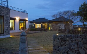 Una casa moderna con un muro de piedra, una estatua de piedra y un sendero de piedra.