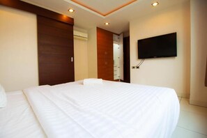 Een hotelkamer met een groot bed, een flatscreen televisie aan de muur en een houten deur.