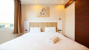 A hotel room with a large bed, a headboard, and a painting on the wall. - Hyde Park Residence by PSR ASIA (Pattaya)