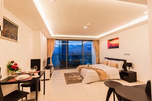 Relax in a spacious room with a large bed, black nightstand, and city view.