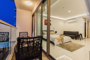 A modern bedroom with a large bed, a sofa, and a dining table with chairs. - Wongamat Tower by Pattaya Sunny Rentals (Pattaya)
