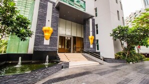 A modern building with a stone facade, a set of stairs leading to a door, and a small water feature in front. - Wongamat Tower by Pattaya Sunny Rentals (Pattaya)