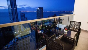 A balcony with a glass railing overlooking a cityscape at dusk. - Wongamat Tower by Pattaya Sunny Rentals (Pattaya)