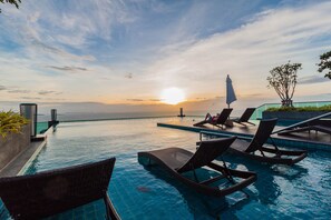 A poolside area with lounge chairs and a view of the sunset over the water. - Wongamat Tower by Pattaya Sunny Rentals (Pattaya)