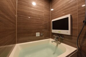 A modern bathroom with a freestanding bathtub, a wall-mounted digital mirror, and a visible water heater control panel. - Hotel Gransky - Adults Only (Tokyo)