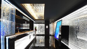 A modern hotel lobby with a reflective black floor, a reception desk, and a large digital screen displaying a blue interface. - Hotel Gransky - Adults Only (Tokyo)