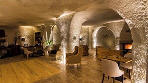 Un int érieur spacieux avec de hauts plafonds et des murs en pierre naturelle, comprenant une cheminée, des coins salon et un plancher en bois.