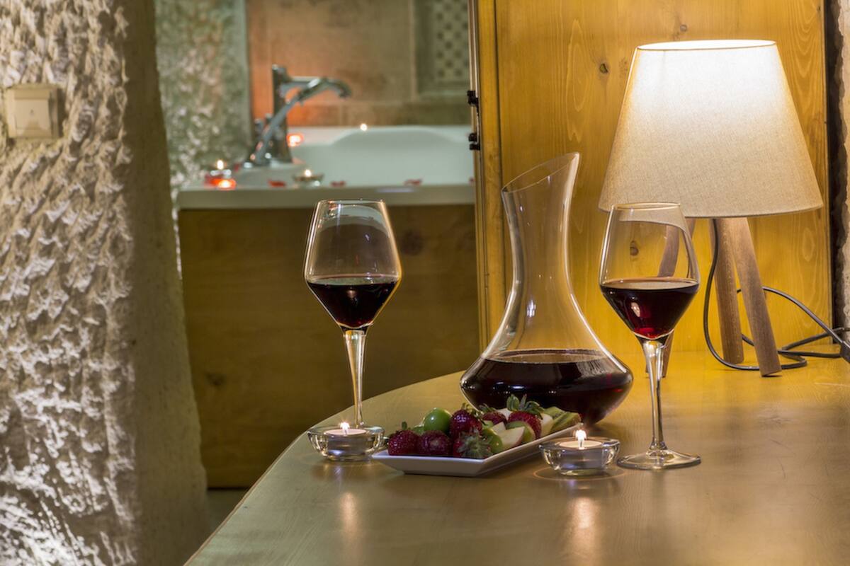 A table with two wine glasses, a candle, and a fruit platter.