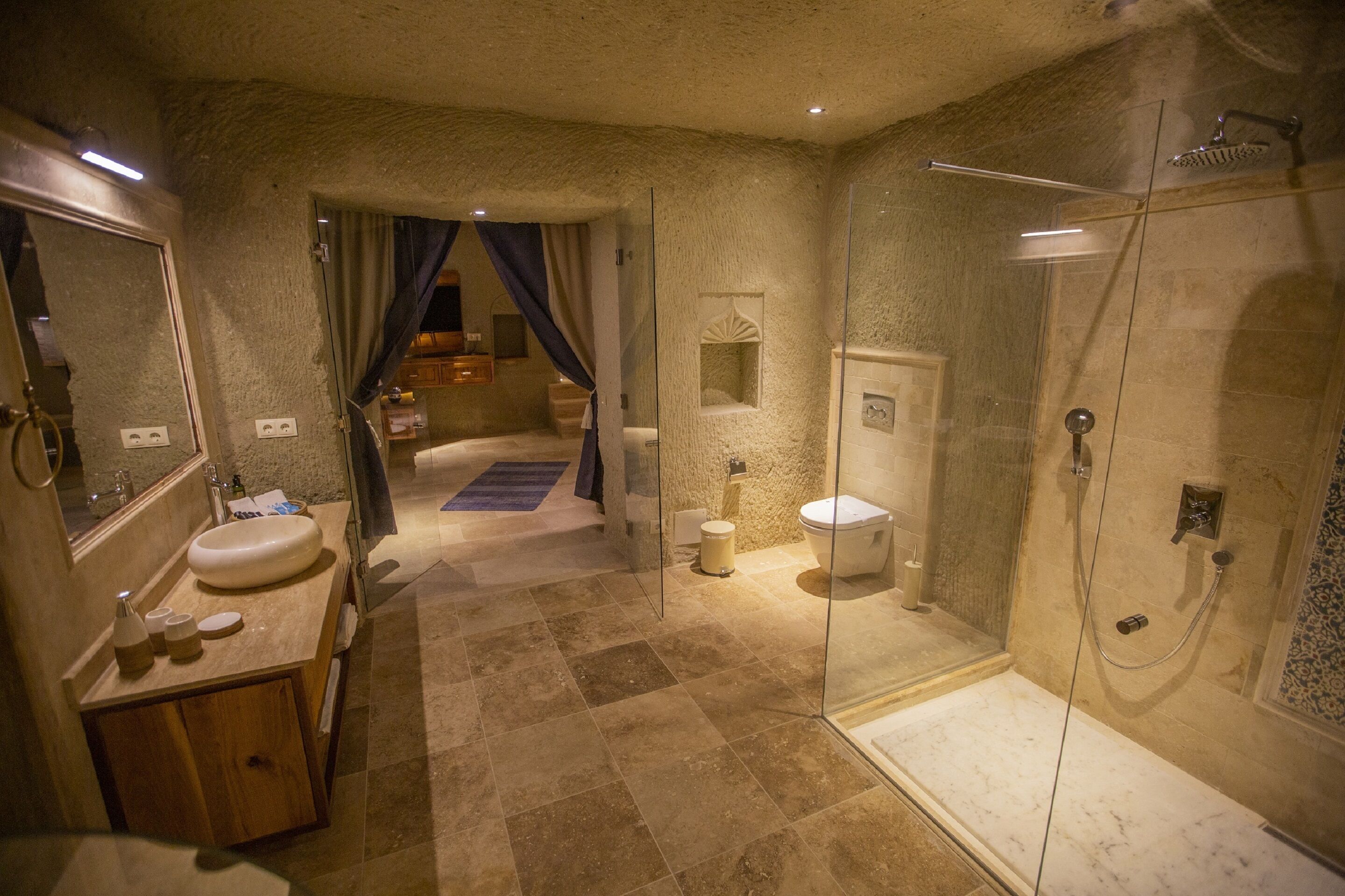 A bathroom with a marble sink, a glass shower enclosure, and a separate toilet area.