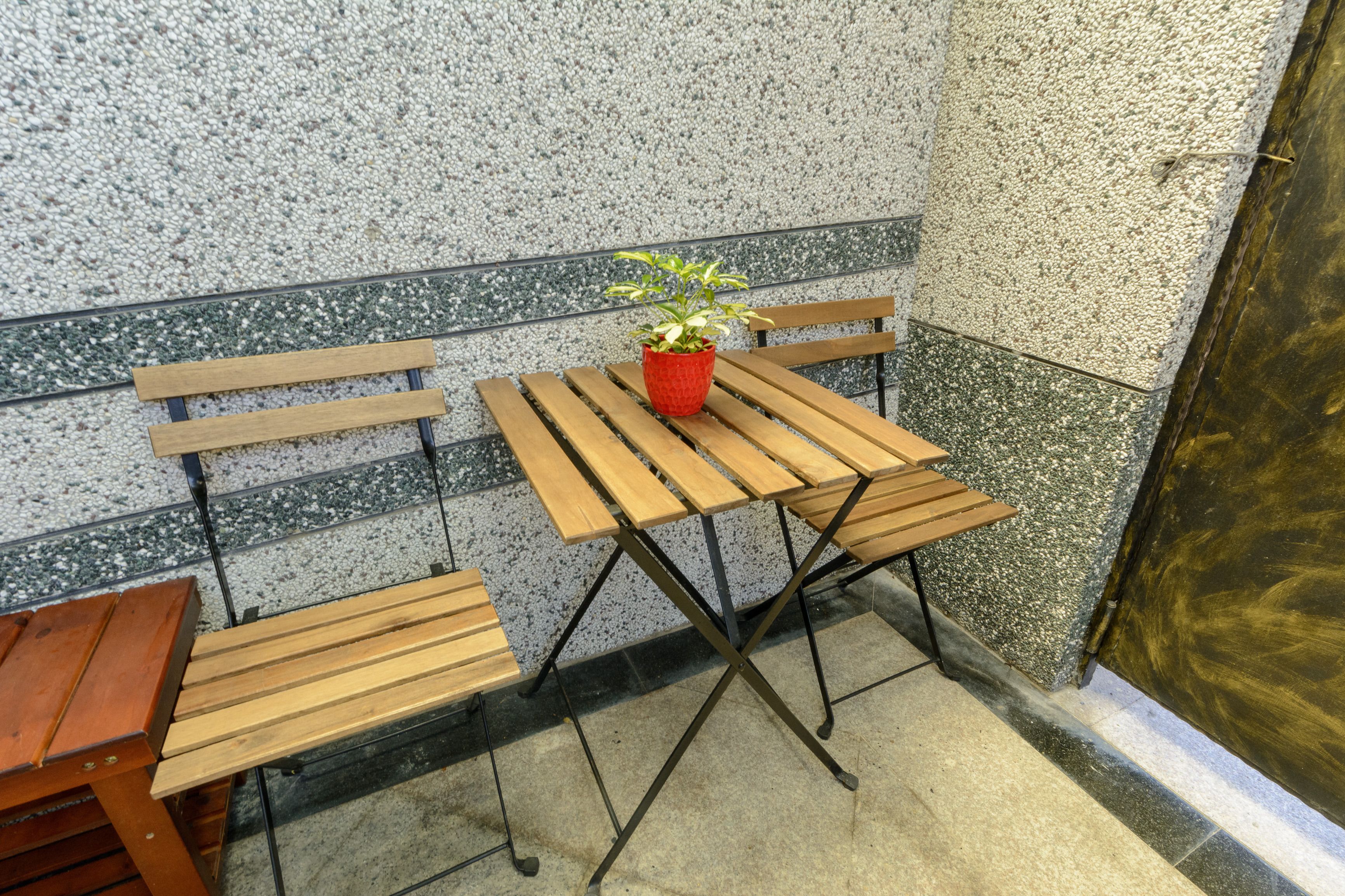 A corner seating area with wooden benches and a small table, a potted plant, and a textured wall.