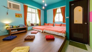 Una habitación con paredes verde mar, piso de madera, dos camas con ropa de cama naranja, un escritorio con lámpara y una ventana con cortinas.