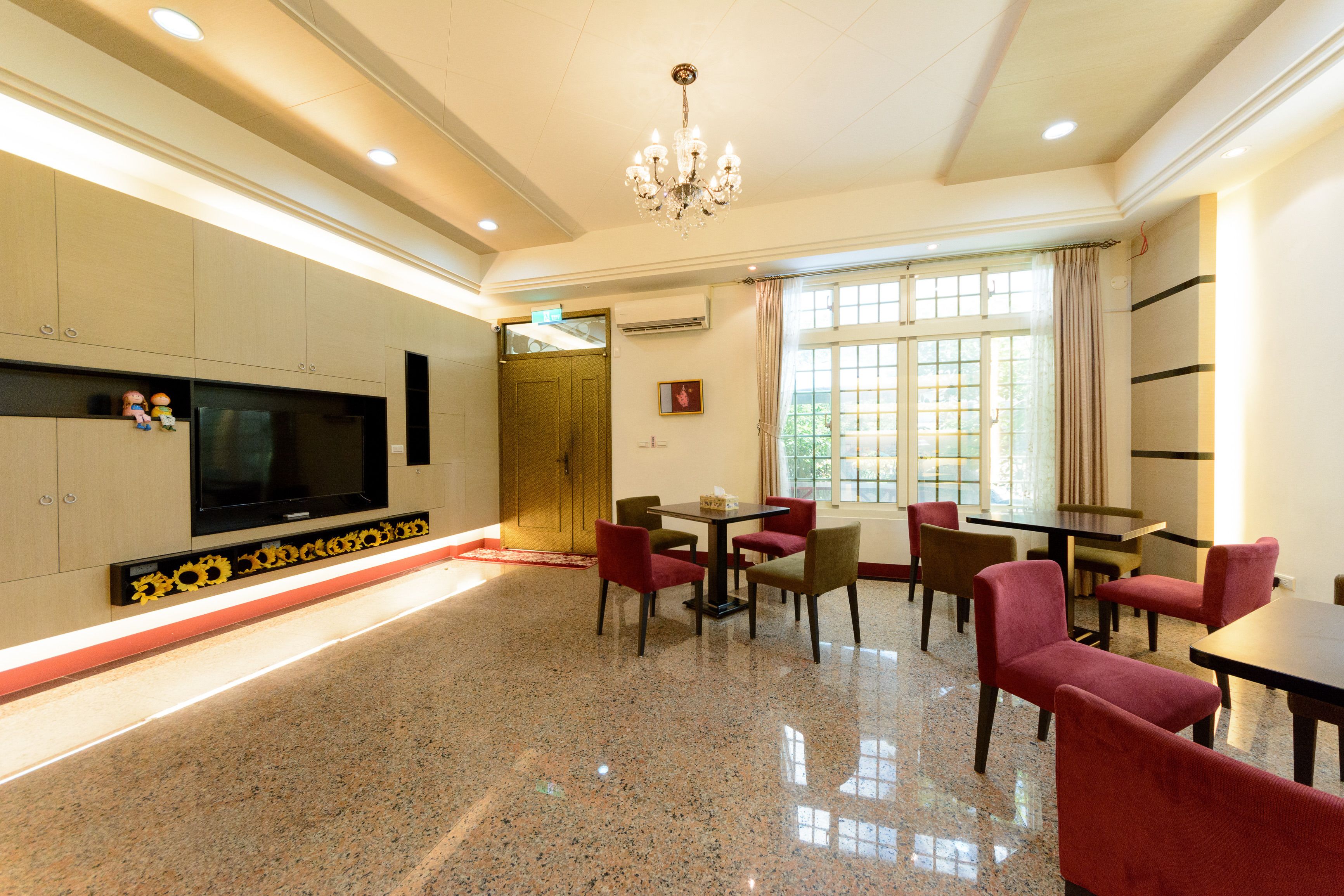 Una habitación amplia con una gran televisión de pantalla plana, un candelabro y un comedor con sillas rojas y una mesa.