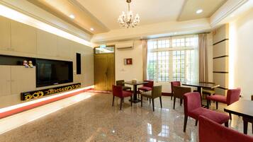 Una habitación amplia con una gran televisión de pantalla plana, un candelabro y un comedor con sillas rojas y una mesa.