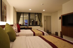 Une chambre d’hôtel avec deux lits, une télévision et une fenêtre avec des rideaux.
