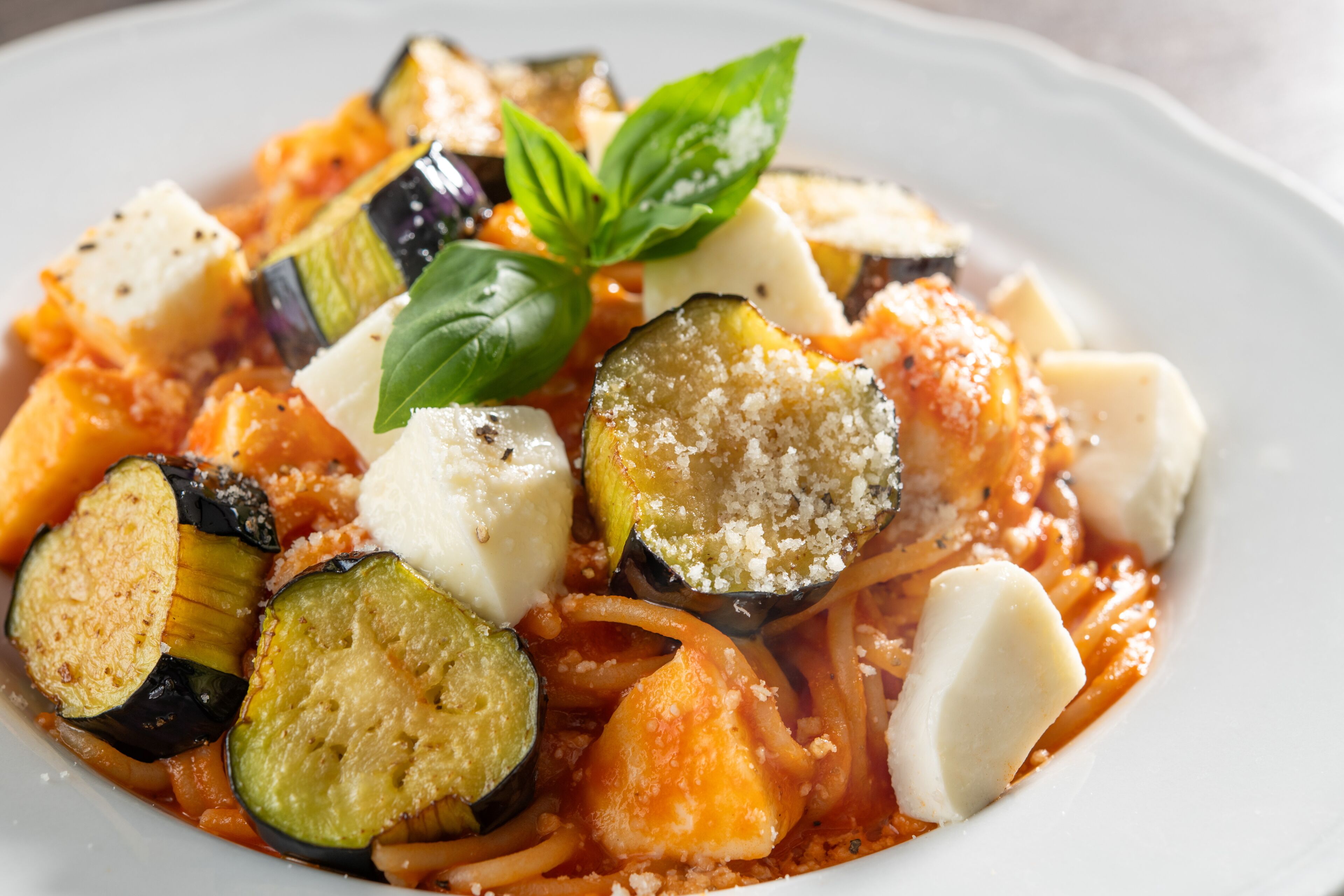 Un plato de espagueti con verduras y queso.