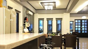Een moderne keuken met een marmeren aanrecht, een eetgedeelte met rieten stoelen en grote ramen.