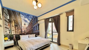 Een hotelkamer met een bed, een bureau, een stoel, een raam met gordijnen en uitzicht op gebouwen.