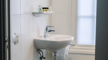 A bathroom with a white sink, a mirror, and a window.