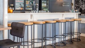 Un espace bar avec des tabourets en bois, un comptoir et un luminaire suspendu.