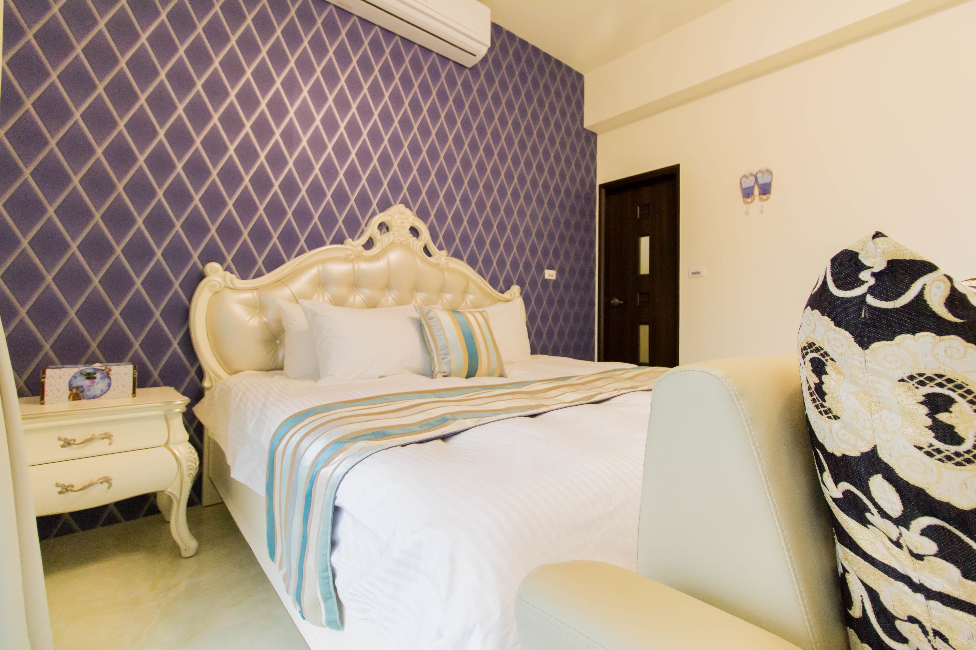 A bedroom with a bed, nightstand, and a chair.