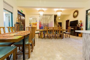 A spacious living room with a wooden dining table, chairs, a TV, and a staircase. - Shan Hai B&B (Ji'an)