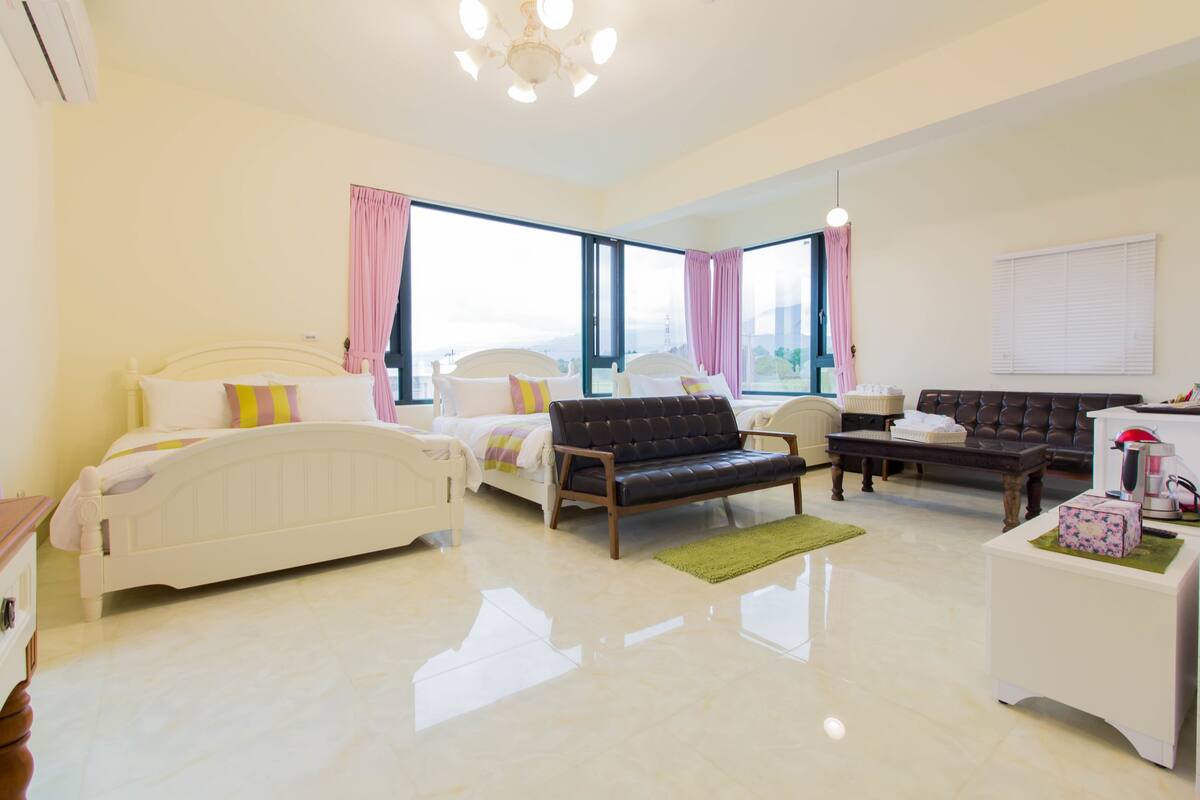 Una habitación de hotel con cama, sofá, mesa de centro y una mesita con lámpara.