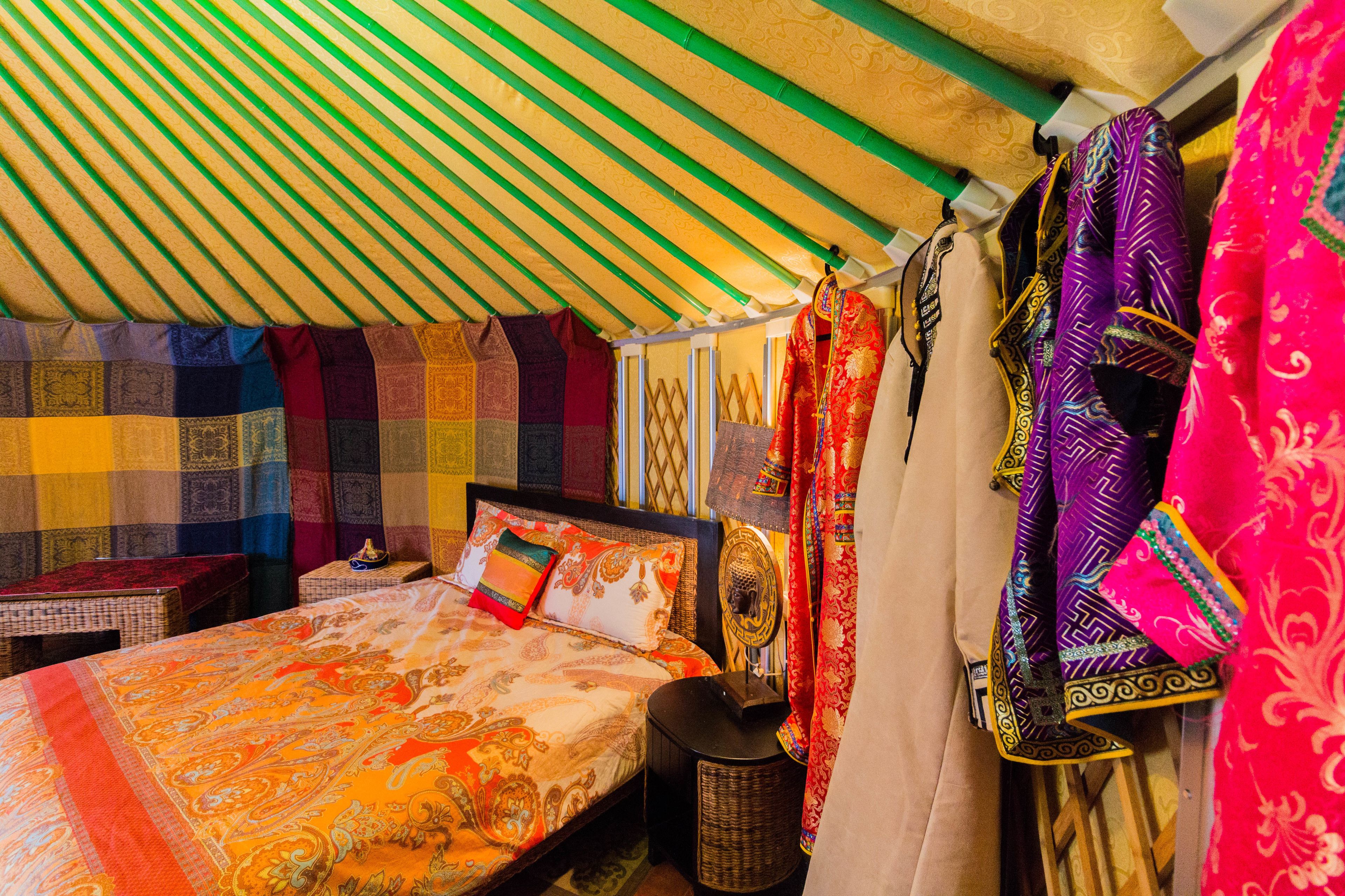 A room with a bed, a small table, and a hanging tapestry.