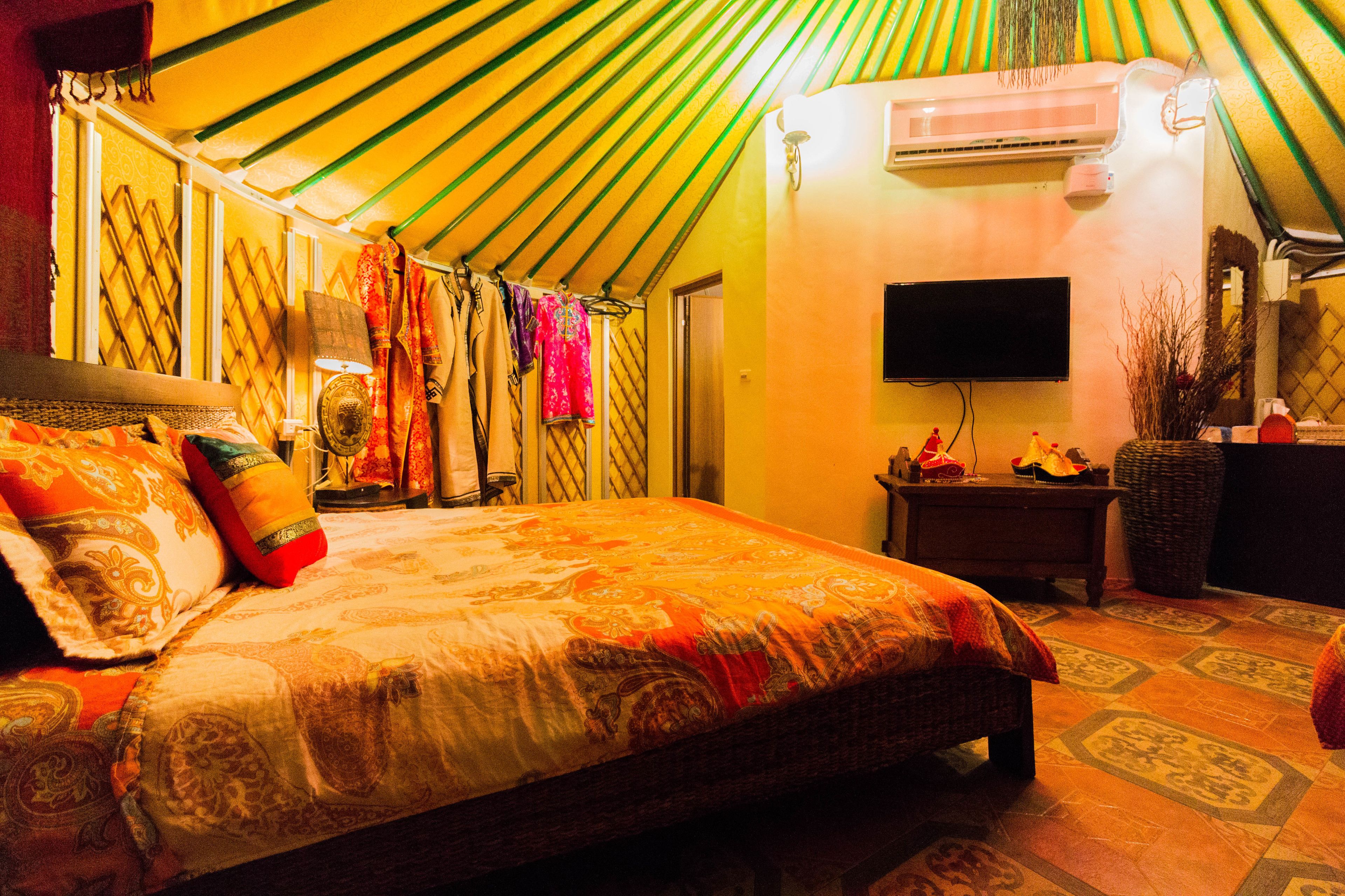 A room with a bed, a television, a wall-mounted air conditioner, and a patterned floor.