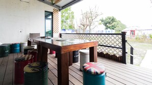 Een houten terras met een tafel en stoelen, omringd door vaten en een lattenhek.