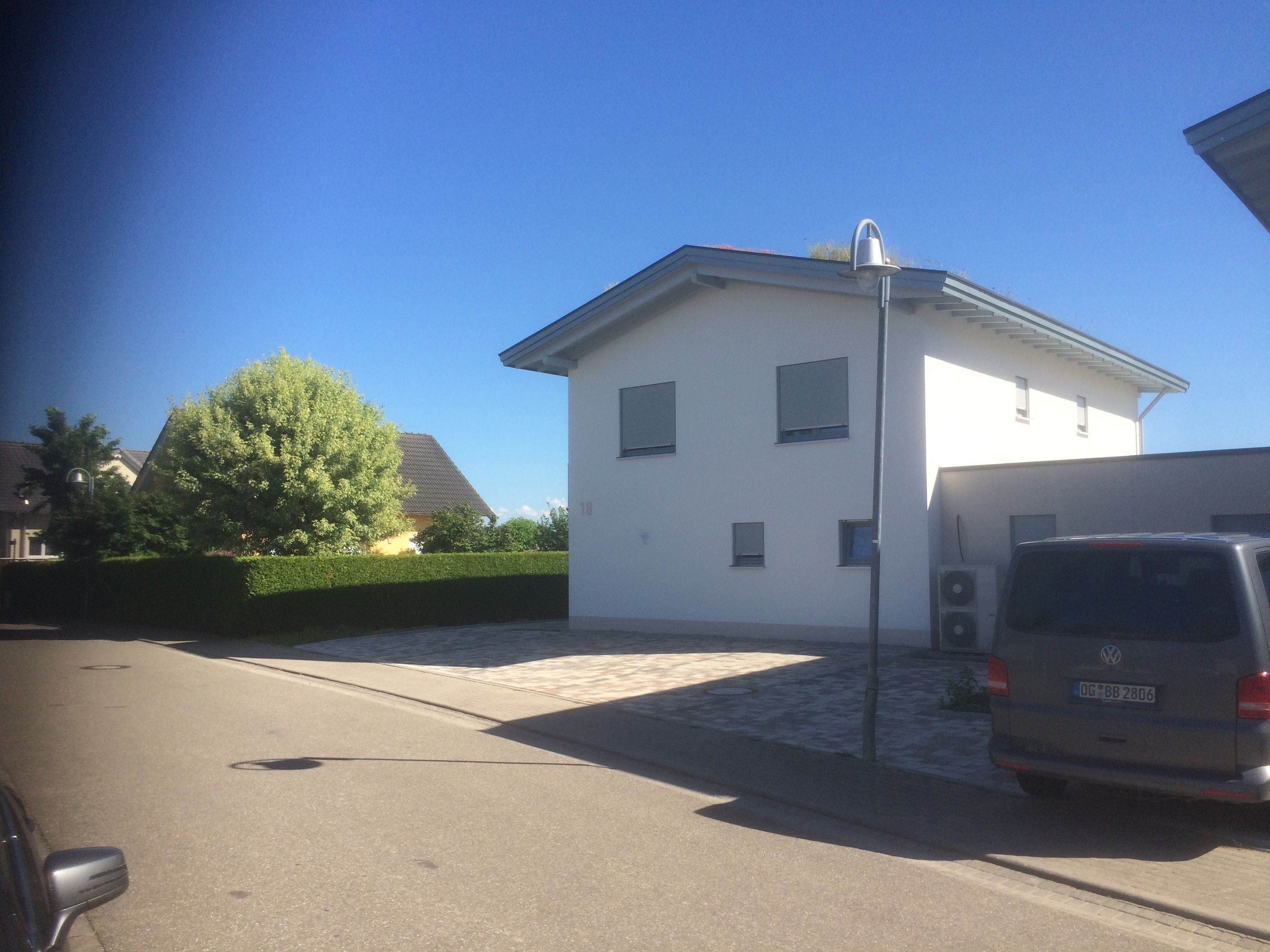 A modern two-story house with a white exterior, a garage, and a parked van.