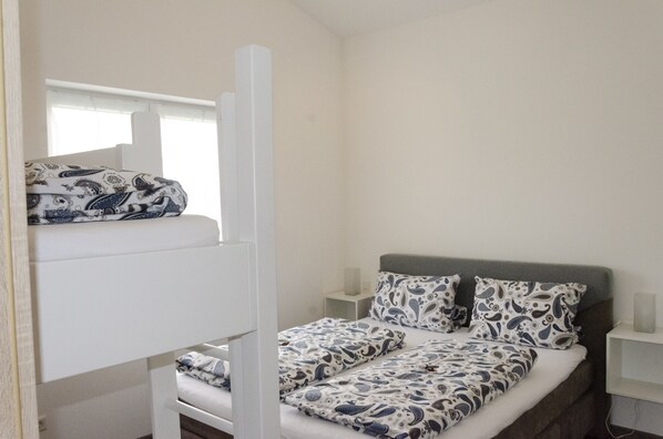 Una habitación con literas, una mesita de noche y una mesilla auxiliar.