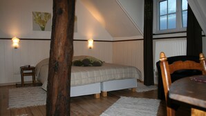 Makuuhuoneessa on puulattia, vihreä tyyny sängyllä, pieni yöpöytä ja tuoli.