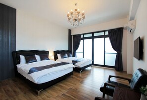 A hotel room with two beds, a chandelier, a large window with curtains, a flat-screen TV, and a seating area. - Chi Ya B&B (Hualien City)