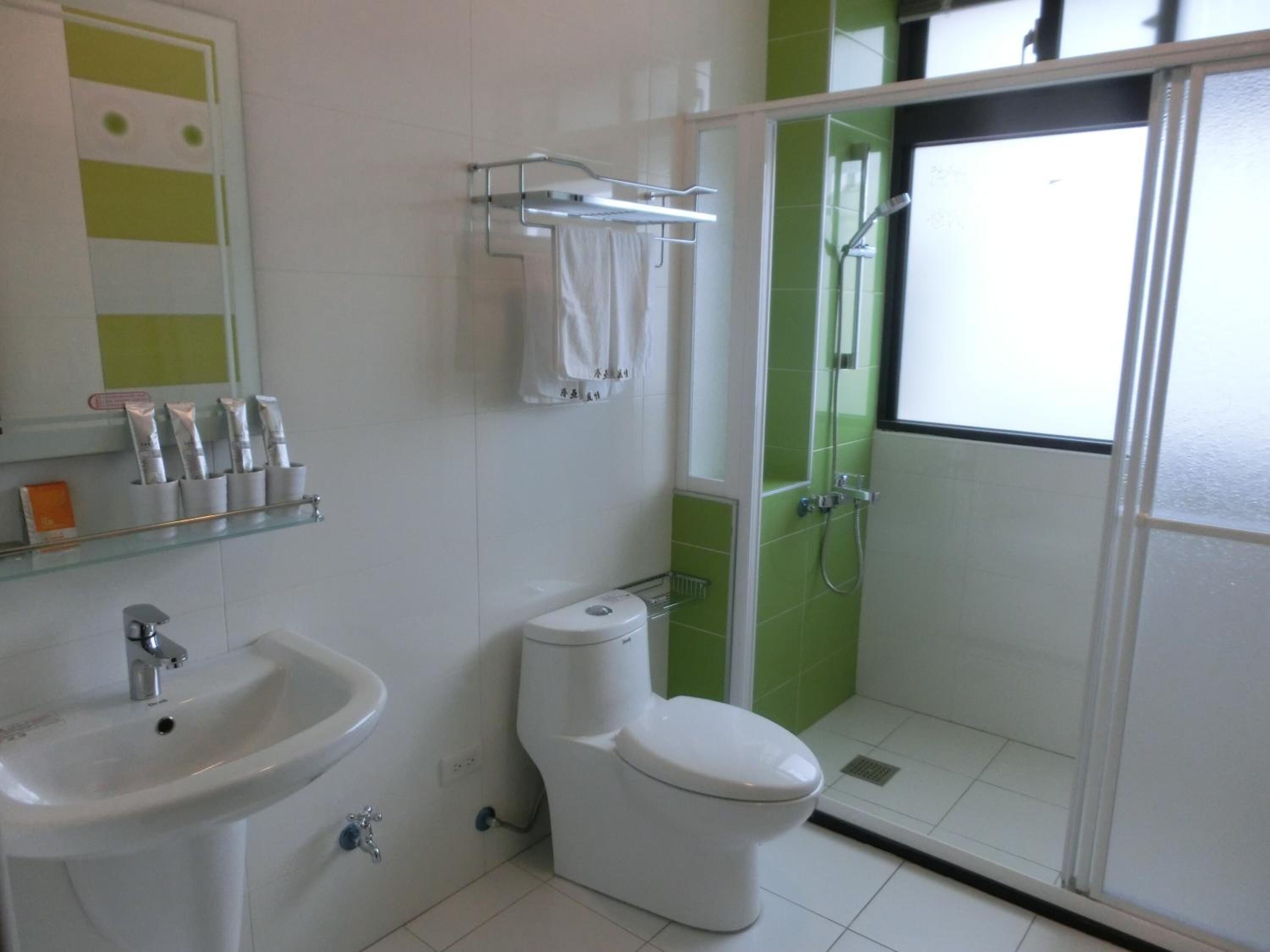 A bathroom with a white sink, toilet, and shower area.