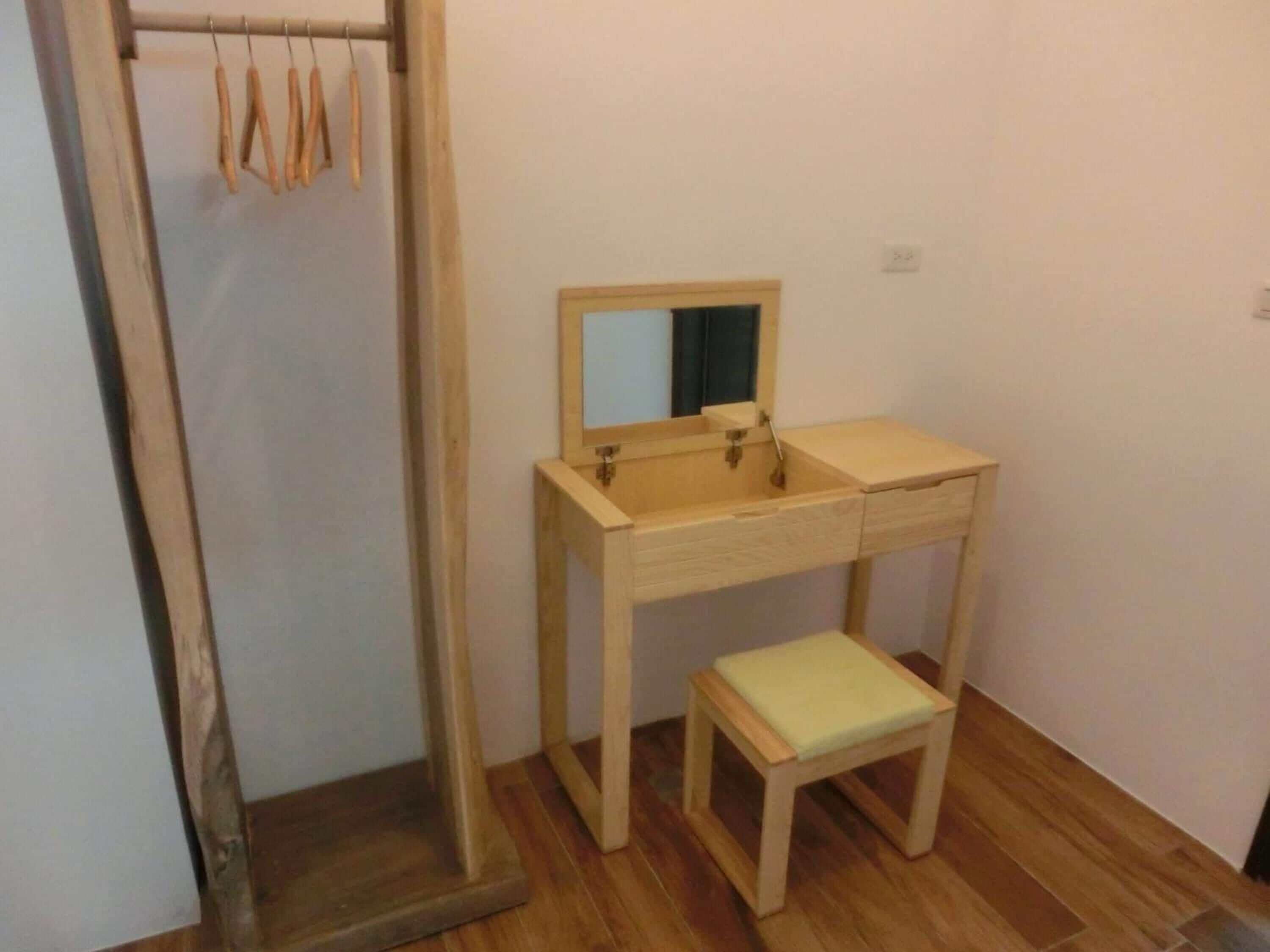 A small bathroom with a wooden vanity, a mirror, and a stool.