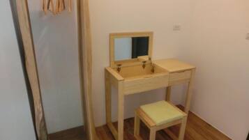 A small bathroom with a wooden vanity, a mirror, and a stool.