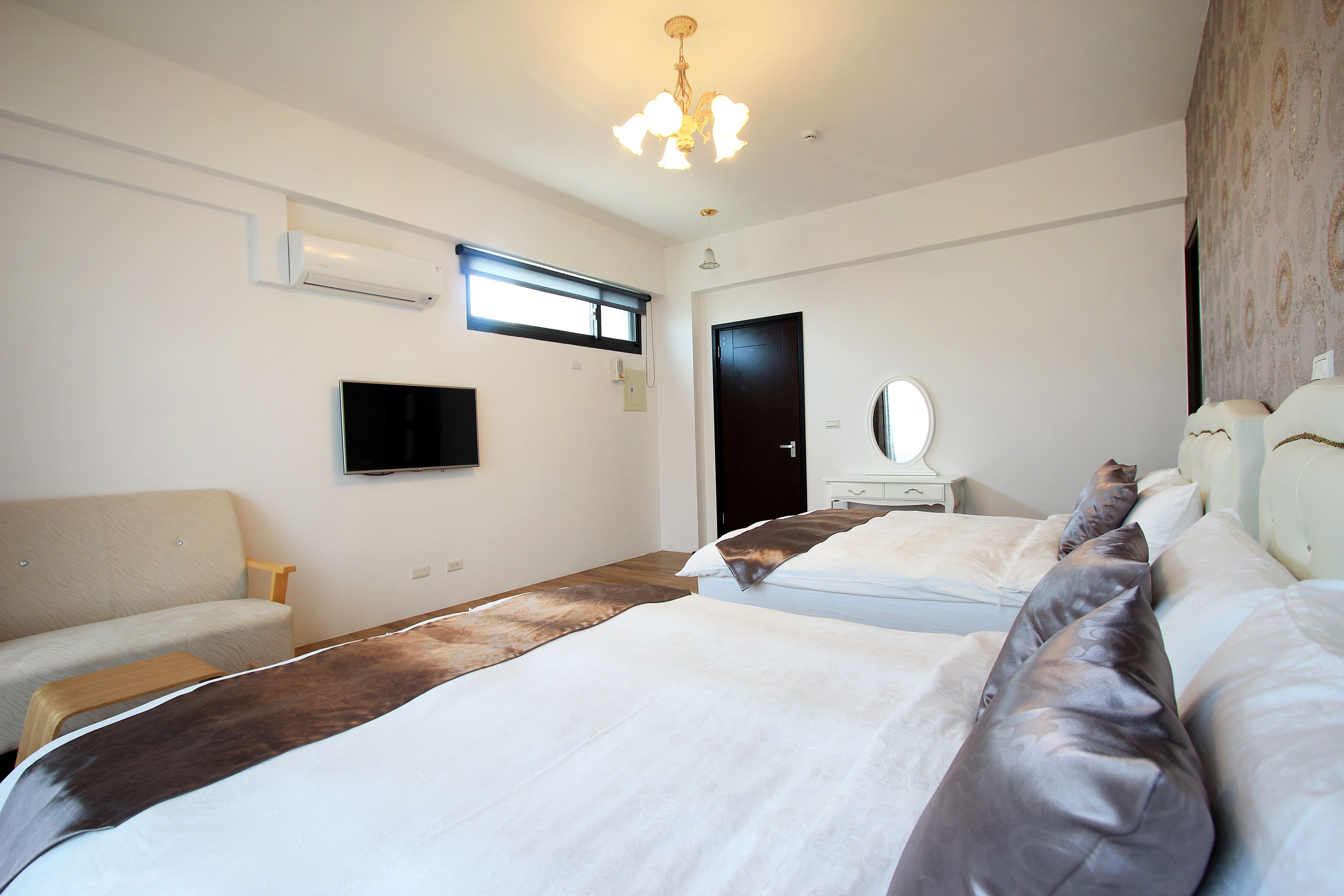 A hotel room with two beds, a flat-screen TV, a ceiling fan, and a window with blinds.