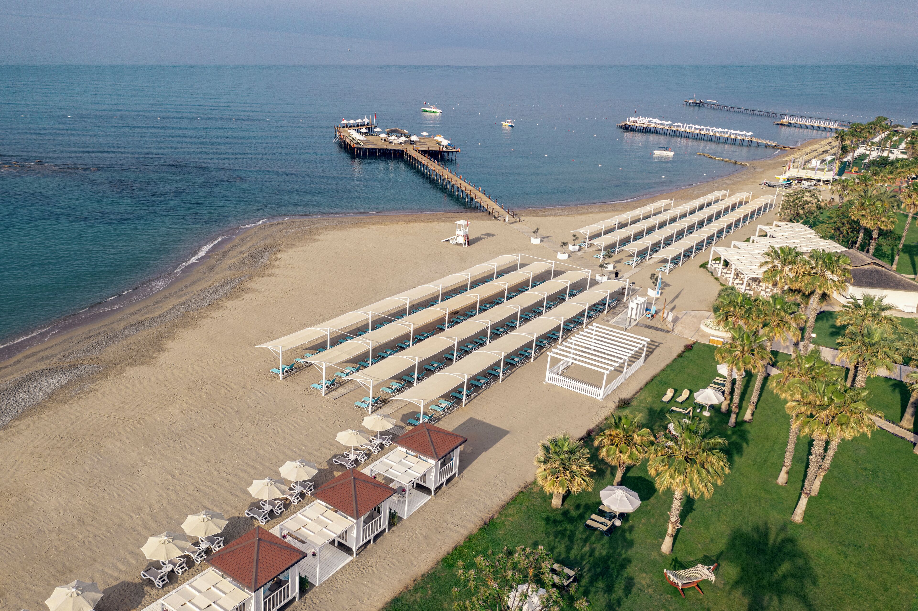 Privat strand, sort sand, solsenger og parasoller