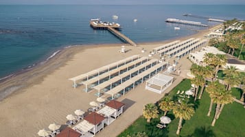 Privat strand, sort sand, solsenger og parasoller