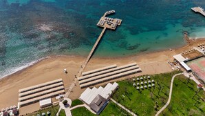 An aerial view of a beach resort with a pier, beach umbrellas, and a tennis court. - Arcanus Hotels Sorgun - All Inclusive (Manavgat)