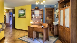 A wooden desk with a computer, a bookshelf, and a cabinet in a room with yellow walls and a tiled floor. - Hostal Almadiero (Burgui)