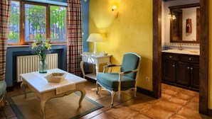 A room with a dining table, a chair, a vase with flowers, a lamp, and a kitchen area with cabinets and a countertop. - Hostal Almadiero (Burgui)