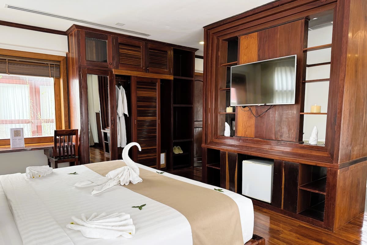 Una habitación de hotel con una cama, armario de madera y televisor.