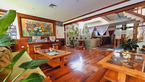 A spacious lobby with wooden flooring, a reception desk, and a large floral painting. - Maison Saiko Angkor Boutique (Siem Reap)