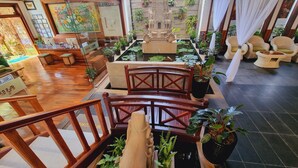 A spacious lobby with a wooden floor, seating areas, a decorative fountain, and various potted plants. - Maison Saiko Angkor Boutique (Siem Reap)