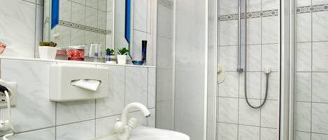A bathroom with a white sink, a mirror, and a glass-enclosed shower.