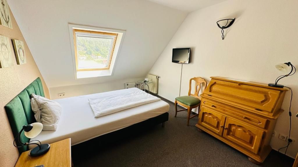 Ein Zimmer mit einem Bett, einem Sessel, einem Schrank, einem Fernseher und einem Fenster.